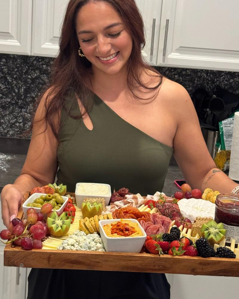Geraldine, co-founder of Aura Gourmet, smiling as she holds a large charcuterie board